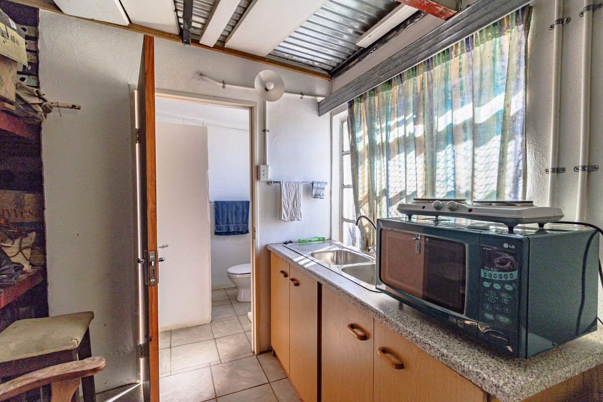 Compact kitchen area featuring a double sink, laminate countertops, and built-in cabinetry, with direct access to an adjacent bathroom.
