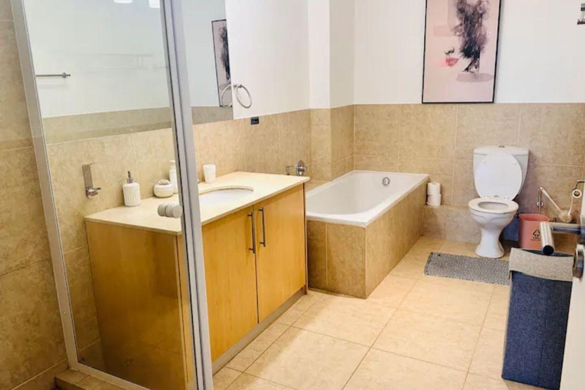 A functional bathroom featuring a built-in vanity with storage, a tiled bathtub, and a separate shower enclosure with glass doors.