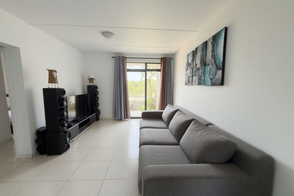 A bright and spacious living room featuring neutral floor tiles and large sliding glass doors that provide natural light and access to the outdoors.