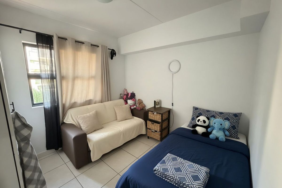 A compact bedroom featuring tiled flooring, a window with curtain tracks, and a ceiling-mounted light fixture.