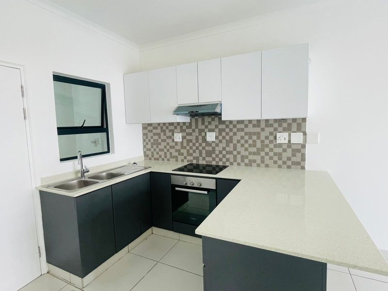 Modern kitchen featuring dark lower cabinetry, white upper cabinets, stone countertops, a built-in oven, hob, extractor fan, and a double sink.