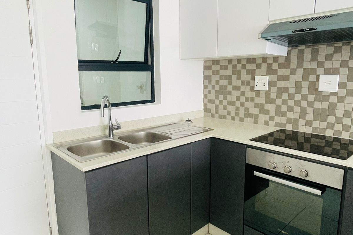 Modern kitchen featuring dark lower cabinetry, white upper cabinets, stone countertops, a built-in oven, hob, extractor fan, and a double stainless steel sink.