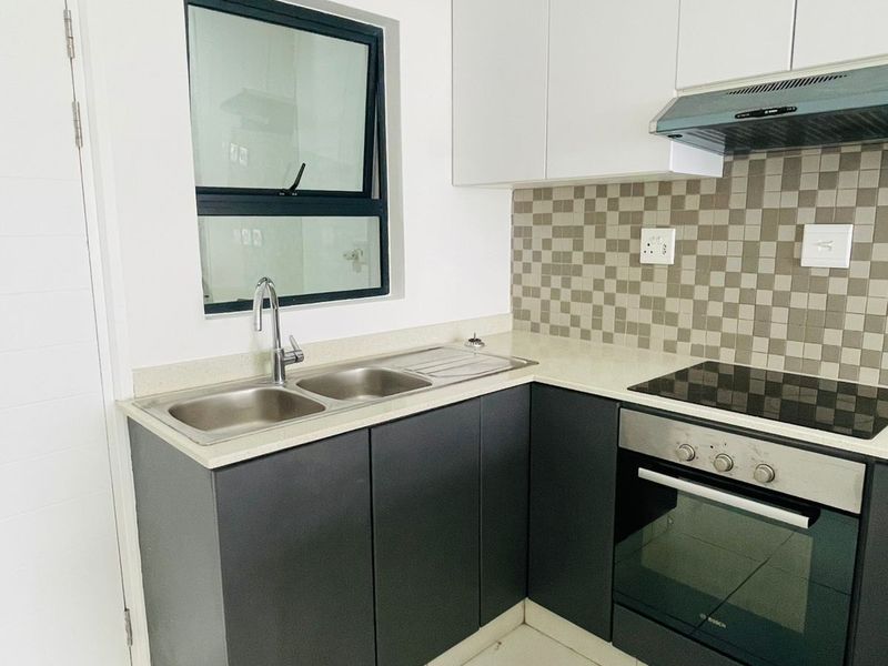 Modern kitchen featuring dark lower cabinetry, white upper cabinets, stone countertops, a built-in oven, hob, extractor fan, and a double stainless steel sink.