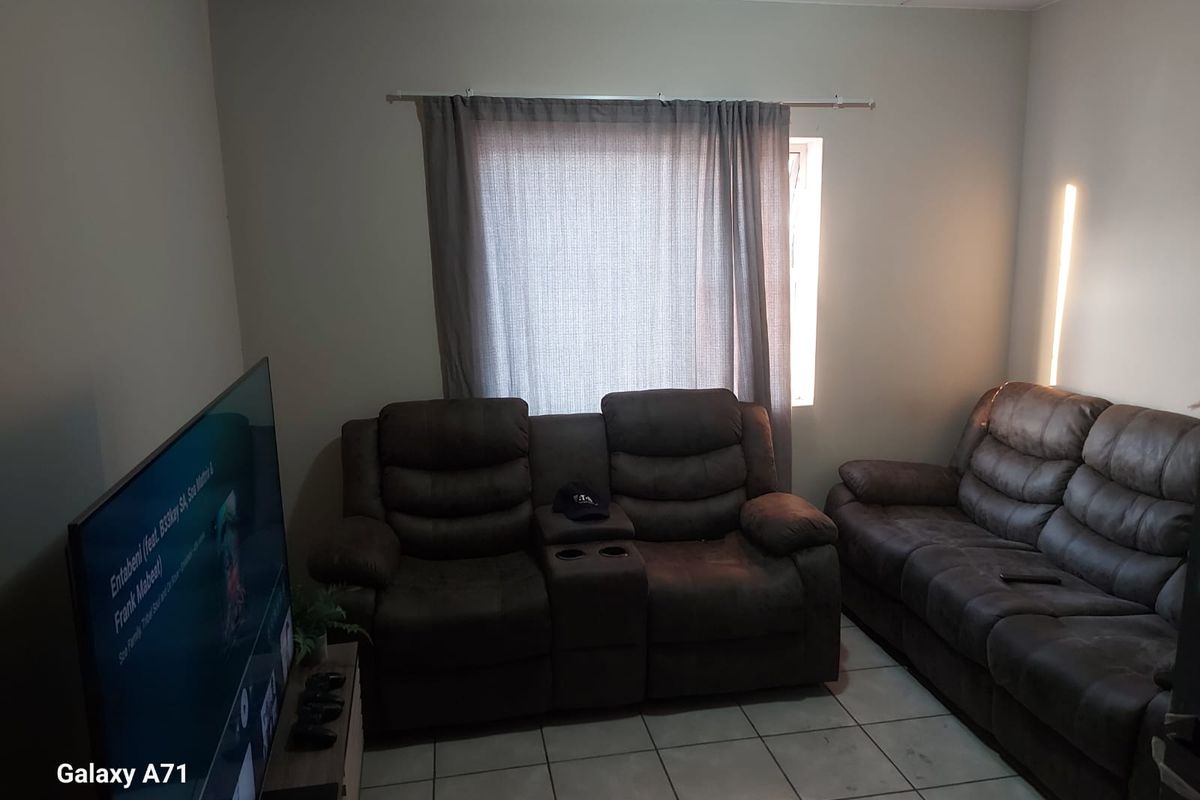 A living room featuring tiled flooring and a window with curtain tracks.