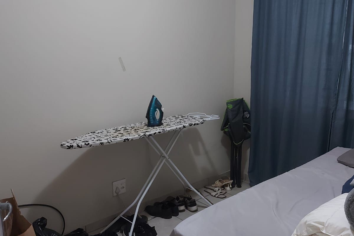 A functional bedroom featuring tiled flooring and a window with curtains, providing a simple and practical living space.