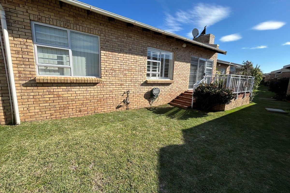 Rear view of the townhouse featuring a brick facade, raised patio area, and a private garden space.