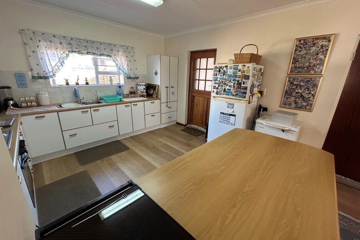 A functional kitchen featuring white cabinetry, laminate countertops, a stainless steel sink, and vinyl flooring, with direct access to an exterior door.