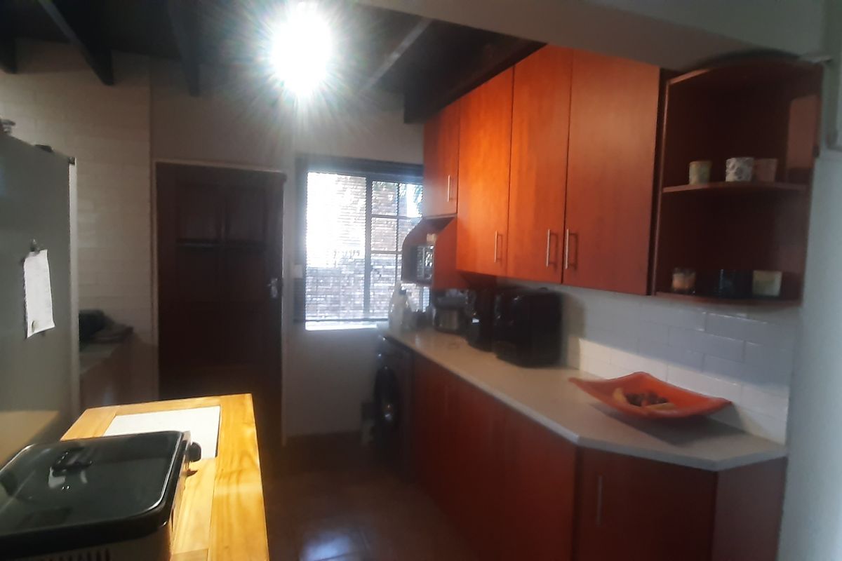 A functional kitchen featuring wooden cabinetry, laminate countertops, and exposed ceiling beams, providing a practical workspace with integrated storage.