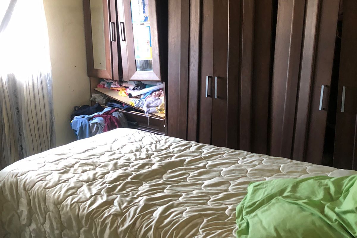 A bedroom featuring built-in wooden cabinetry and an exposed ceiling structure, requiring cosmetic updates to improve the overall finish and condition.