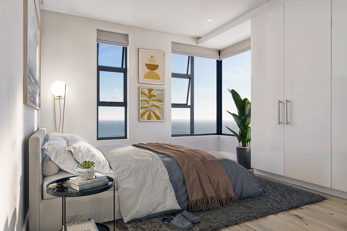 A bright, modern bedroom featuring built-in floor-to-ceiling wardrobes, large windows with ocean views, and high-quality finishes throughout.