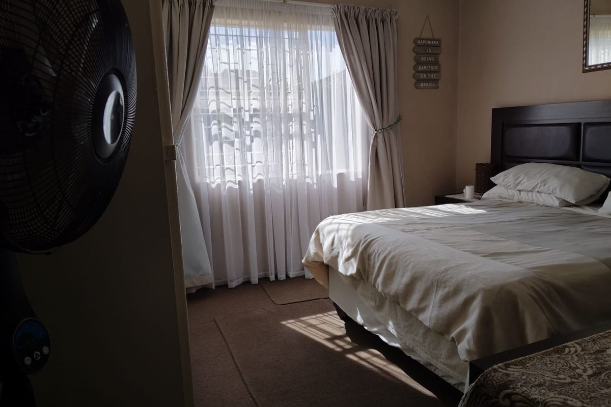 A bedroom featuring carpeted flooring and a window with curtains, providing natural light.