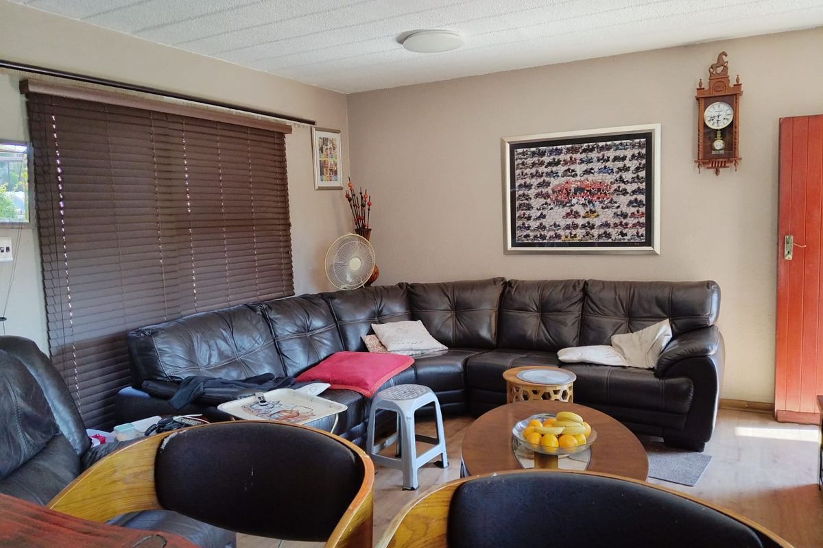 A living room featuring laminate flooring, horizontal window blinds, and a textured ceiling finish.