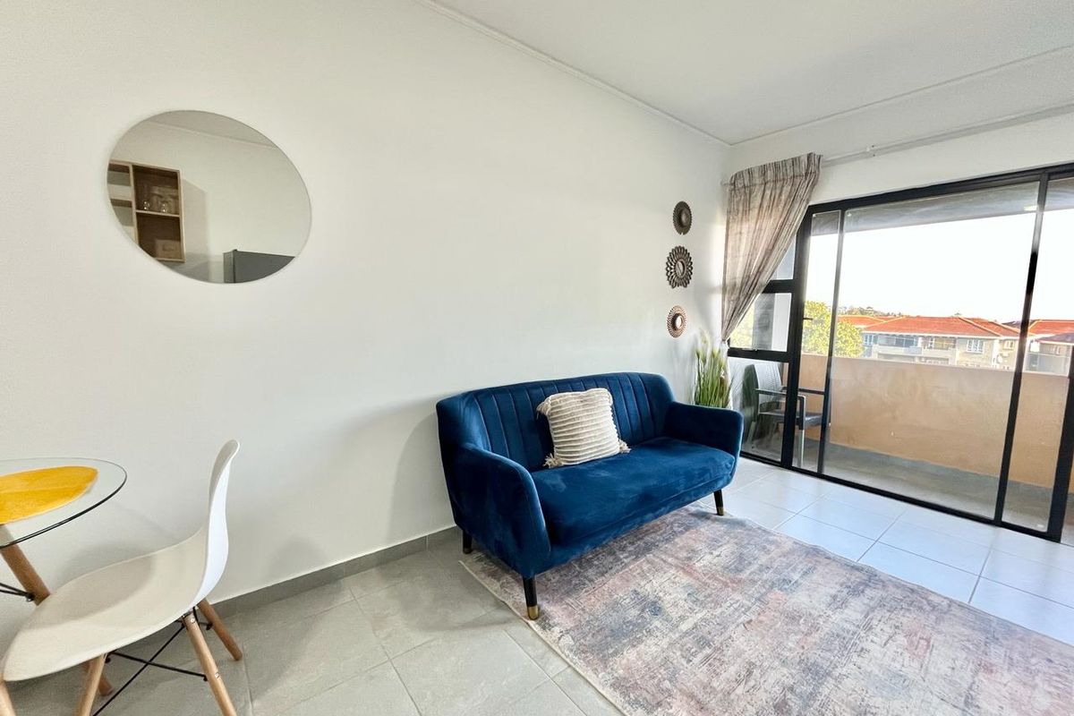 A bright living area featuring tiled flooring and large sliding glass doors that provide access to an outdoor balcony.