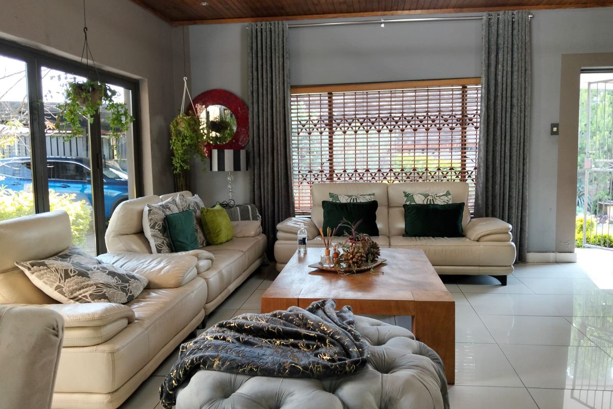 Spacious living room featuring large glass sliding doors, tiled flooring, and a distinctive timber-paneled ceiling with recessed lighting.