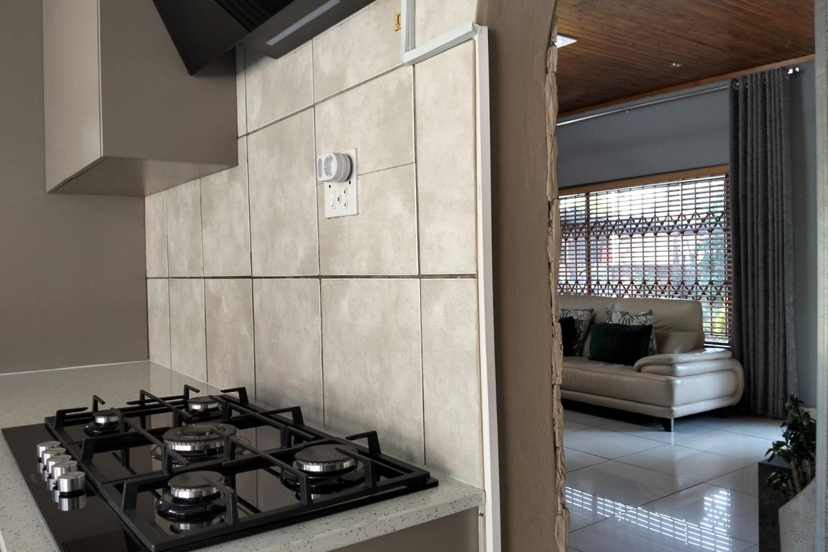 A kitchen area featuring a built-in gas hob and extractor fan, with an arched opening leading into an adjacent living space.