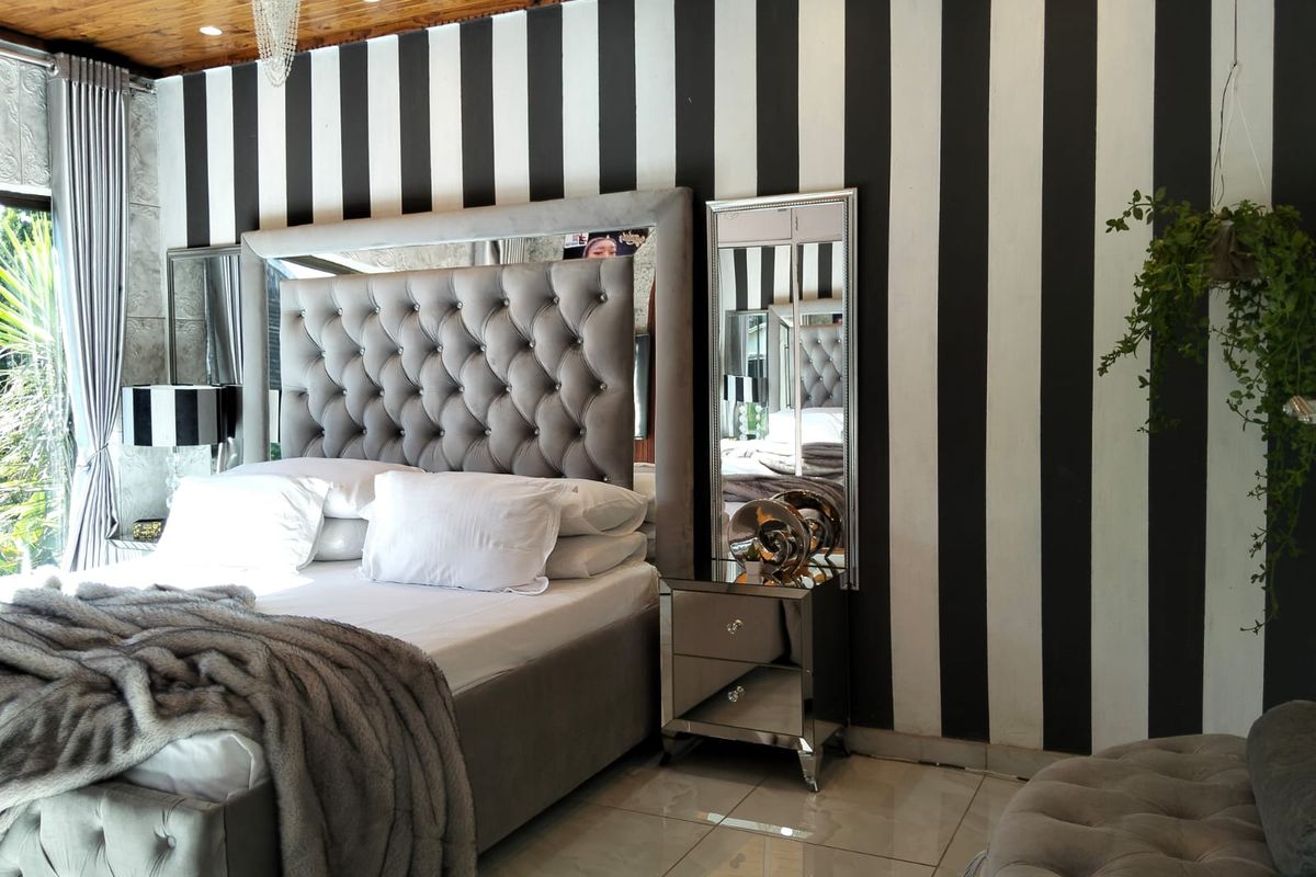 A bedroom featuring a high-gloss tiled floor, a timber-paneled ceiling with recessed lighting, and a bold striped feature wall.