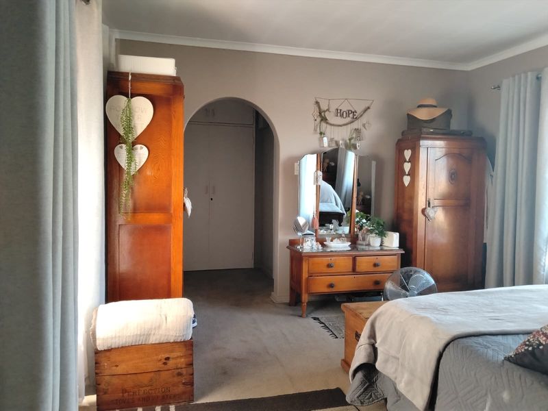 A bedroom featuring an arched doorway leading to a built-in wardrobe area, with neutral wall tones and carpeted flooring.