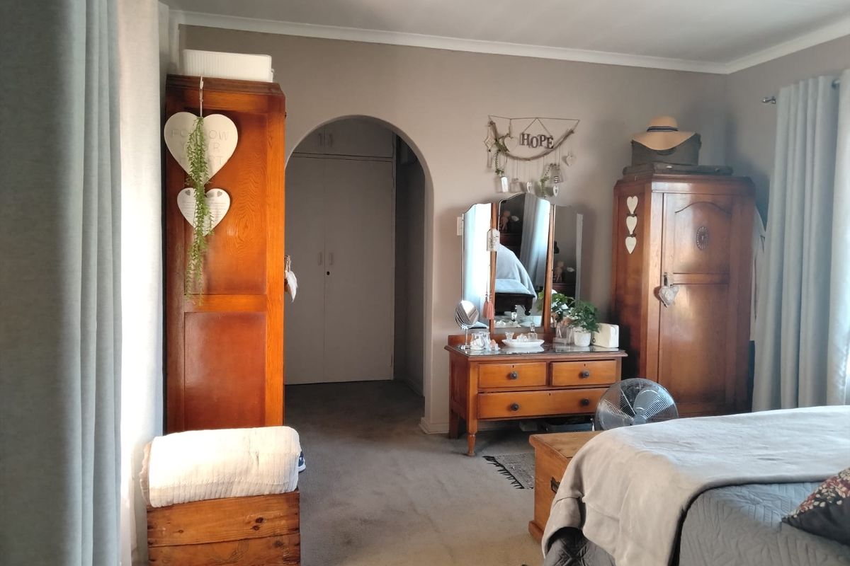A bedroom featuring an arched doorway leading to a built-in wardrobe area, with neutral wall tones and carpeted flooring.