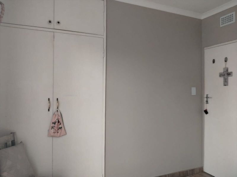 A bedroom interior featuring built-in floor-to-ceiling cabinetry with overhead storage and a standard internal door.