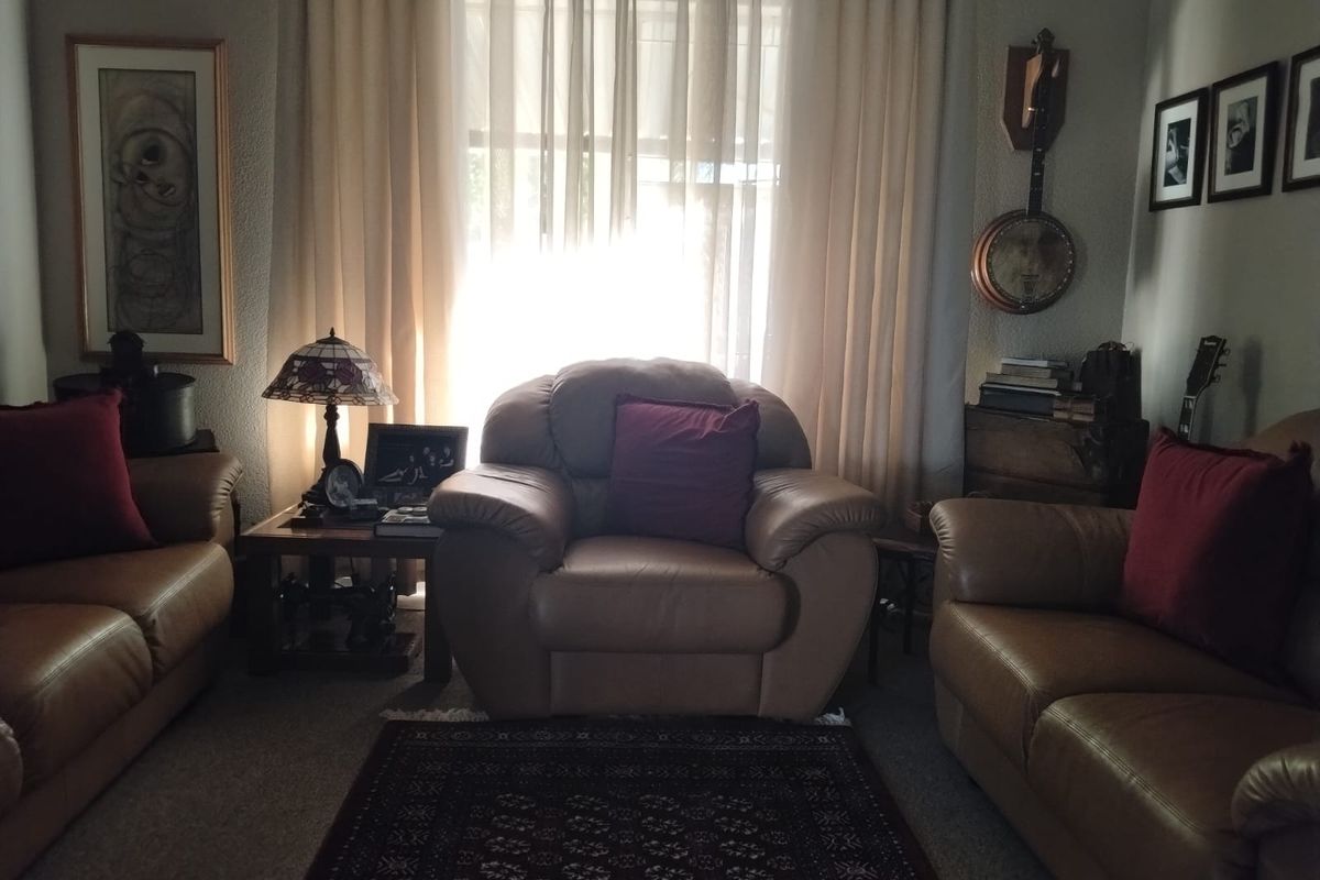 A cozy living room featuring a central window with curtains, providing natural light to the seating area.