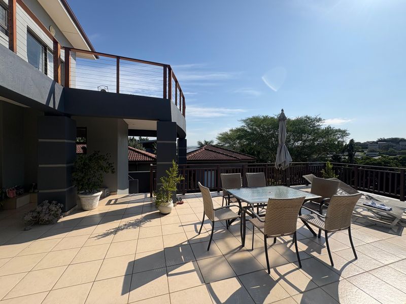 Spacious elevated patio featuring tiled flooring, modern balustrades, and direct access to the upper level of the home.