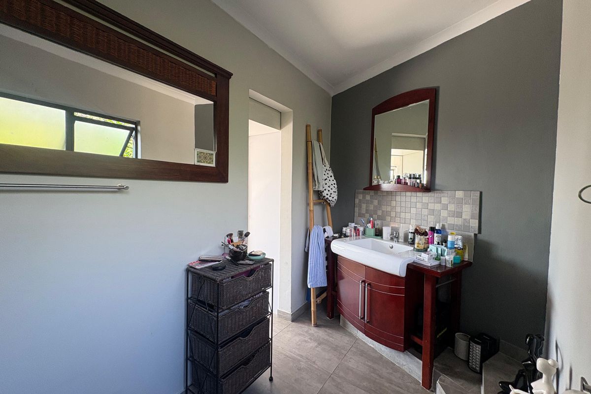 A functional bathroom featuring a vanity with a built-in basin, tiled splashback, and a wall-mounted mirror.