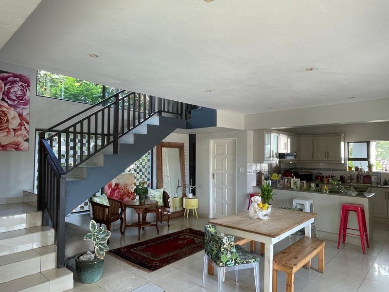 Open-plan living and kitchen area featuring a staircase with metal balustrade, tiled flooring, and integrated kitchen cabinetry.