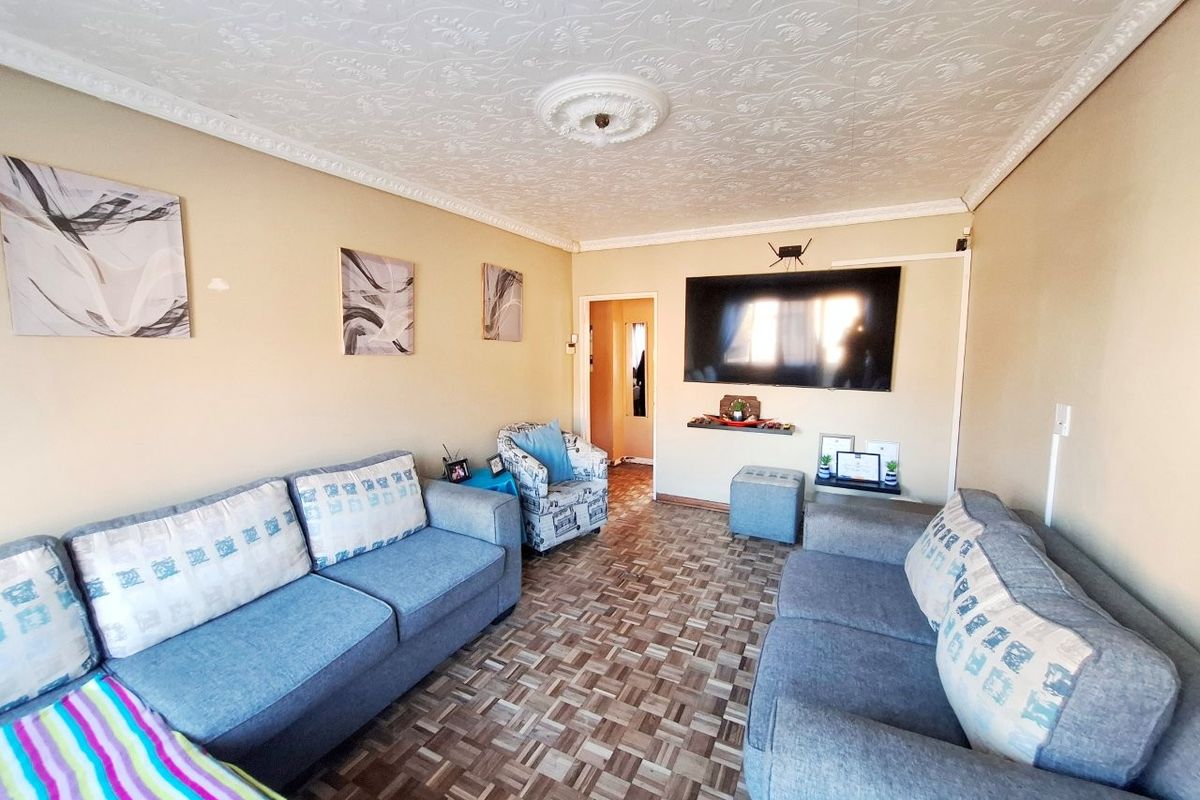 A living room featuring a textured ceiling with a decorative rose, coving, and a wall-mounted television.