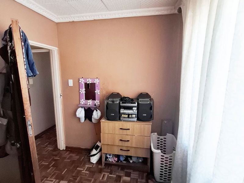 A bedroom featuring parquet flooring and textured ceiling tiles, requiring some maintenance and cosmetic updates to improve the overall aesthetic.
