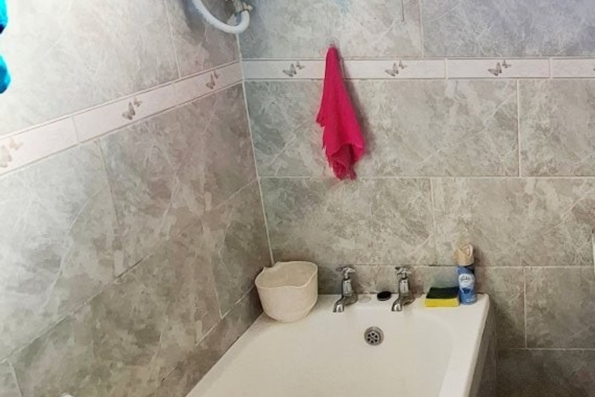 A functional bathroom featuring a standard bathtub, tiled wall finishes, and an exposed electric water heater unit.