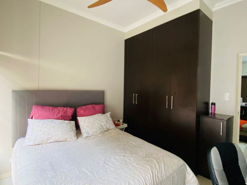 A well-maintained bedroom featuring built-in dark wood cabinetry, a ceiling fan, and tiled flooring.