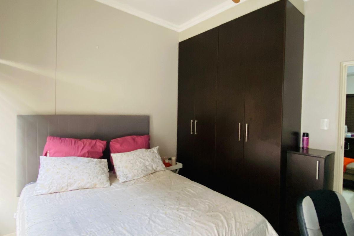 A well-maintained bedroom featuring built-in dark wood cabinetry, a ceiling fan, and tiled flooring.