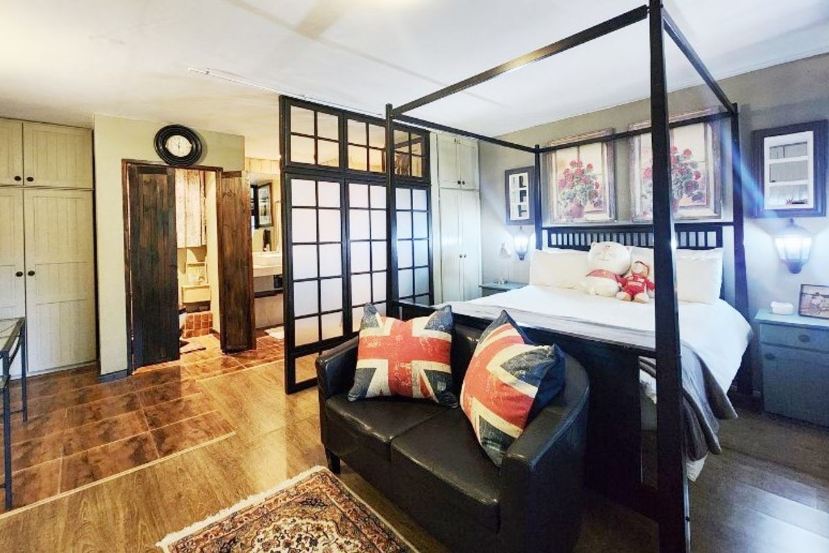 Spacious bedroom featuring built-in cupboards, a decorative room divider, and direct access to an en-suite bathroom with tiled flooring throughout.