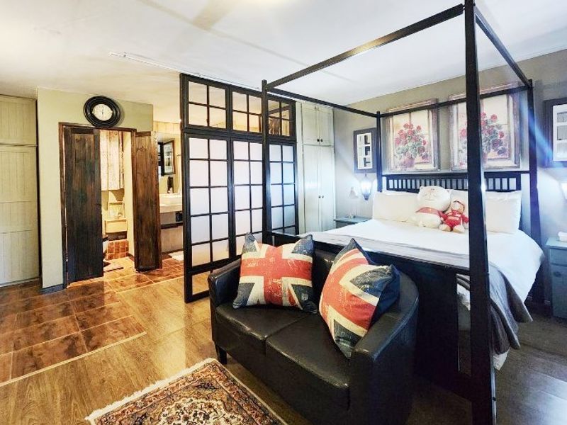 Spacious bedroom featuring built-in cupboards, a decorative room divider, and direct access to an en-suite bathroom with tiled flooring throughout.