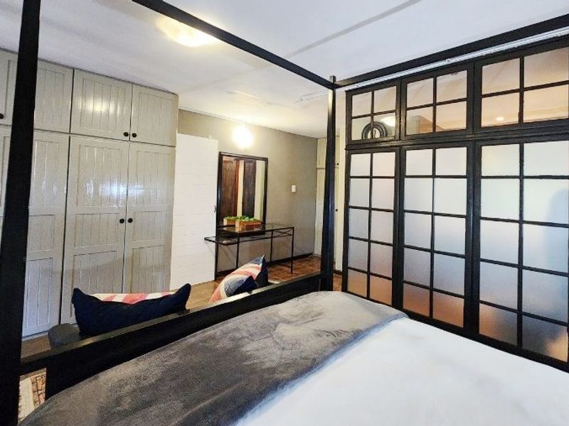 Spacious bedroom featuring extensive built-in cabinetry and a stylish black-framed frosted glass partition, creating a modern and functional living space.