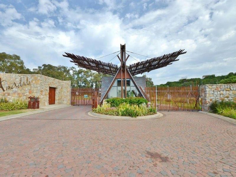 The main entrance to the estate features a paved driveway, stone-clad walls, and a distinctive architectural gate structure.