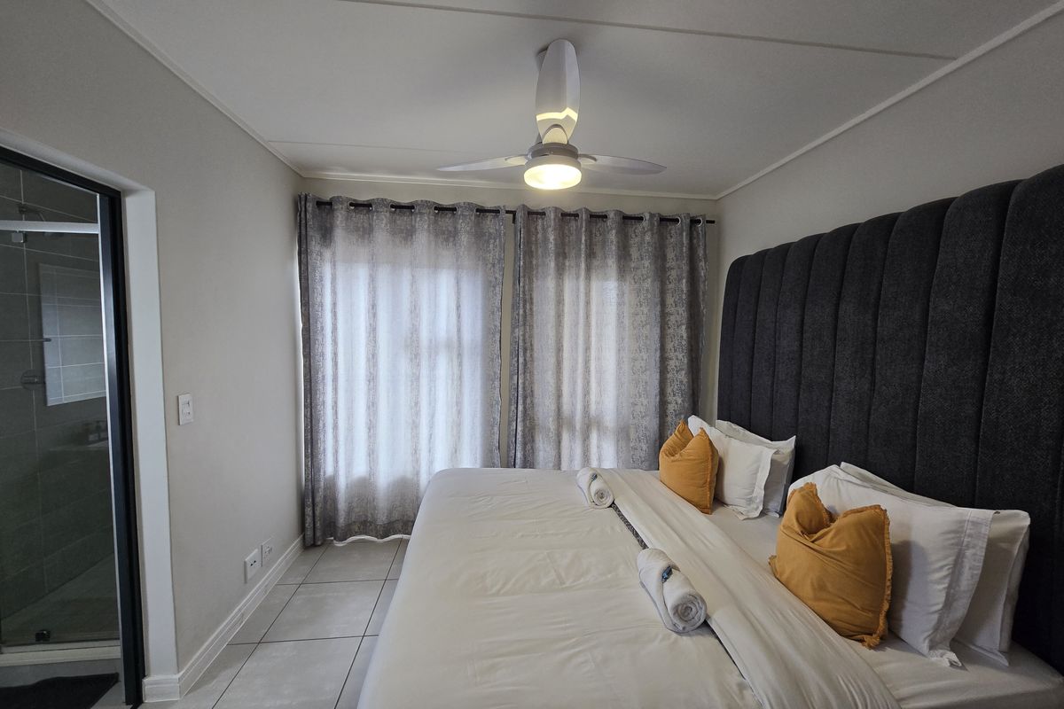 A well-maintained bedroom featuring tiled flooring, a ceiling fan, and direct access to an en-suite bathroom.