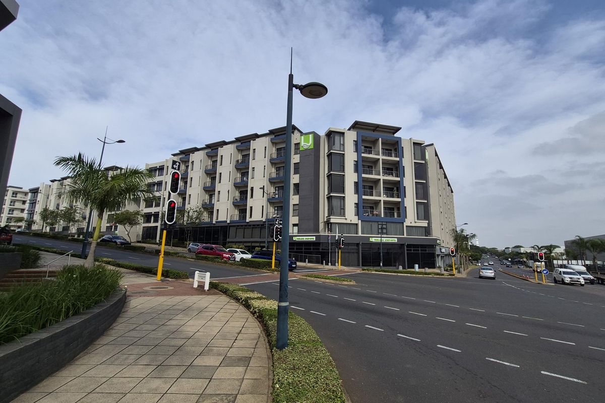 Street view of a modern multi-story apartment complex featuring contemporary architectural design, balconies, and convenient access to local road infrastructure.