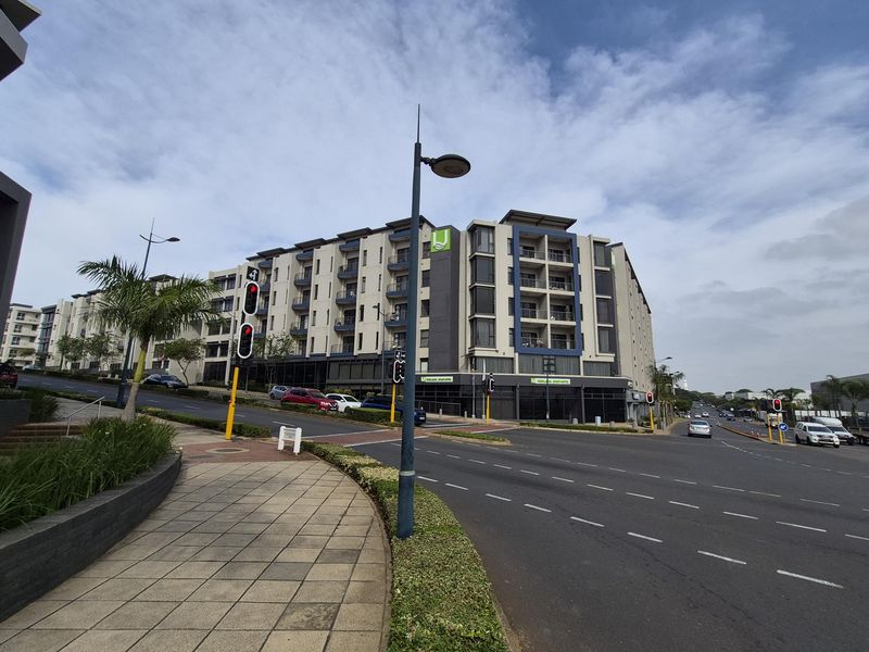 Street view of a modern multi-story apartment complex featuring contemporary architectural design, balconies, and convenient access to local road infrastructure.