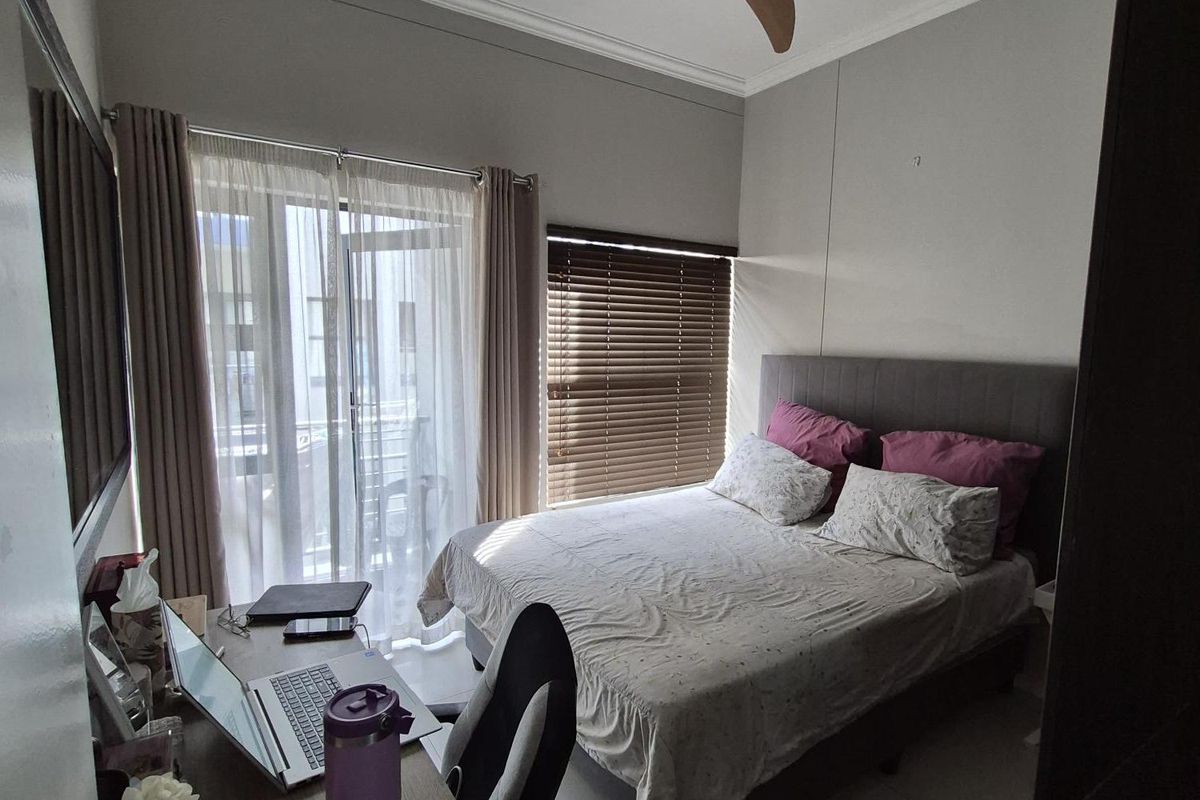 A well-lit bedroom featuring tiled flooring, a ceiling fan, and direct access to a private balcony through sliding glass doors.