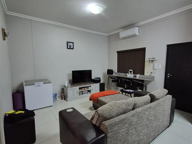Open plan living area featuring tiled flooring, a wall-mounted air conditioning unit, and a built-in breakfast bar counter.