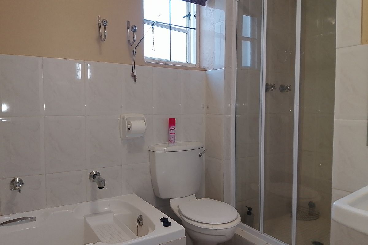 A functional bathroom featuring a built-in bathtub, a separate glass-enclosed shower, and a standard toilet with tiled walls.