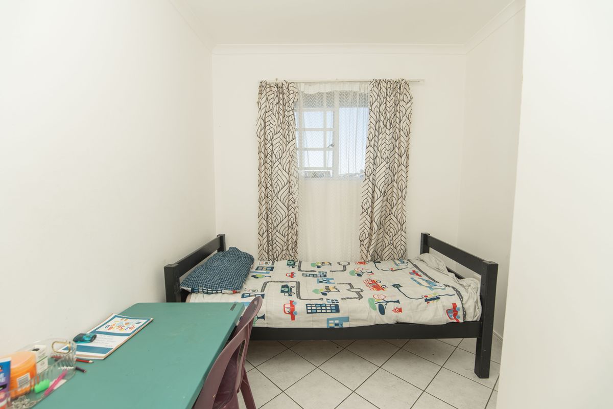 A functional bedroom featuring tiled flooring and a window with curtain fixtures.