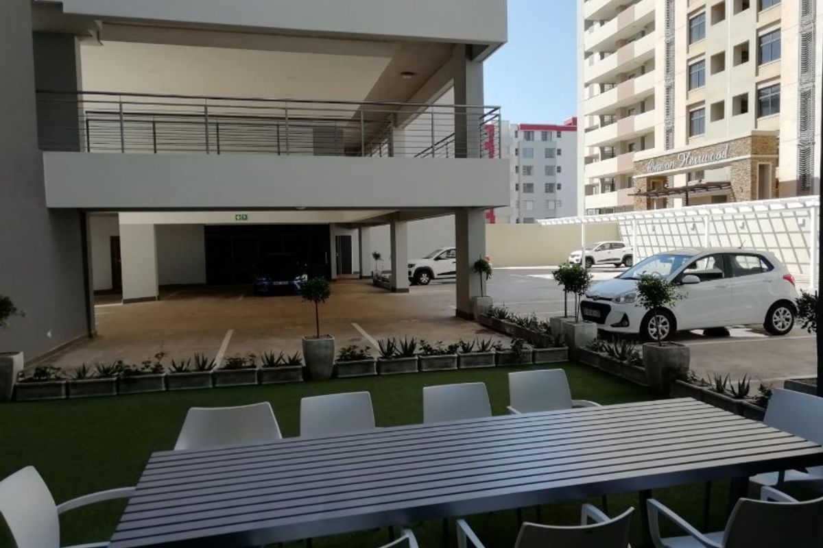 A view of the apartment complex parking area and ground level outdoor space with paved surfaces and modern building architecture.