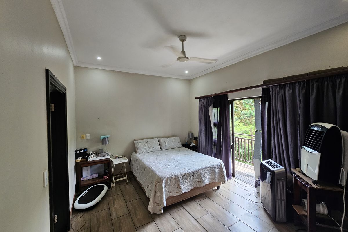 A bedroom featuring tiled flooring, a ceiling fan, and direct access to a private balcony through sliding glass doors.