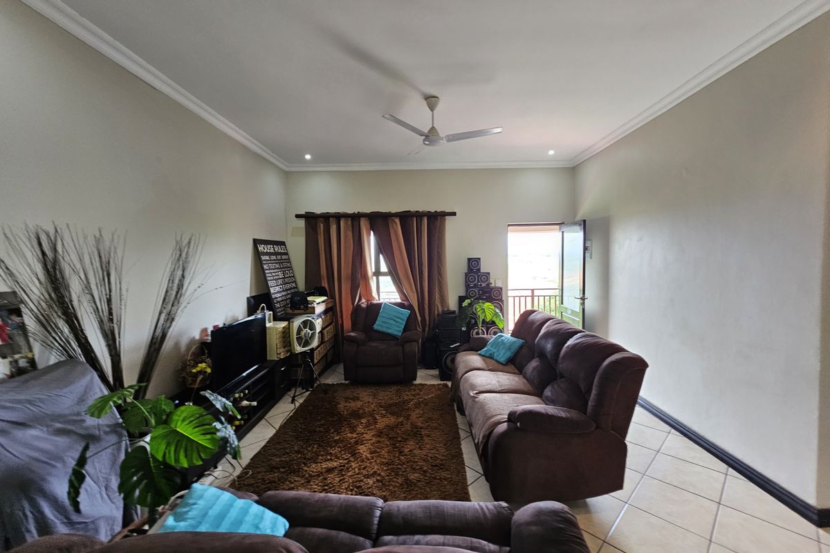 Spacious living room featuring neutral walls, tiled flooring, a ceiling fan, and direct access to an outdoor balcony area.