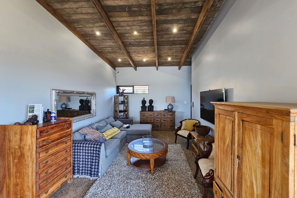 A cozy living room featuring a rustic exposed timber beam ceiling, recessed lighting, and polished concrete flooring.