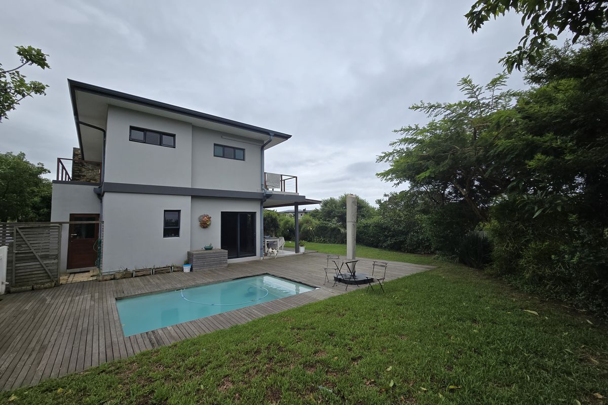 Rear view of the two-story house featuring a swimming pool, timber decking, and a landscaped garden area.