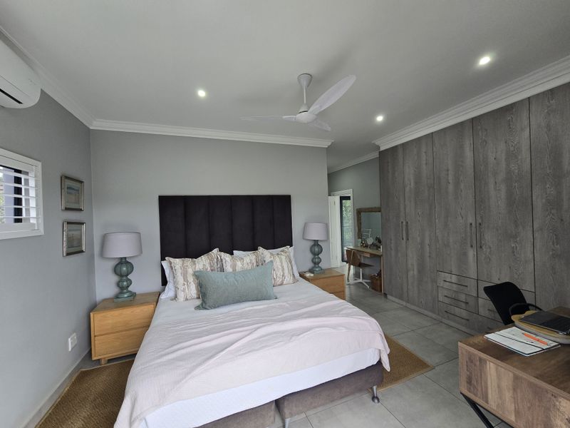 Spacious bedroom featuring built-in floor-to-ceiling cabinetry, tiled flooring, recessed downlighting, and a ceiling fan, offering a clean and modern living space.