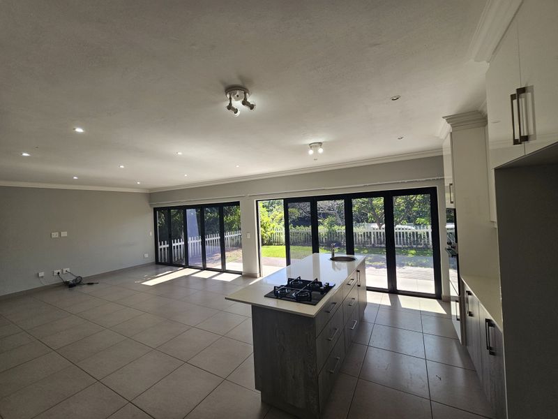 Spacious open-plan living area featuring a modern kitchen with a central island, gas hob, and large folding doors opening to the garden.